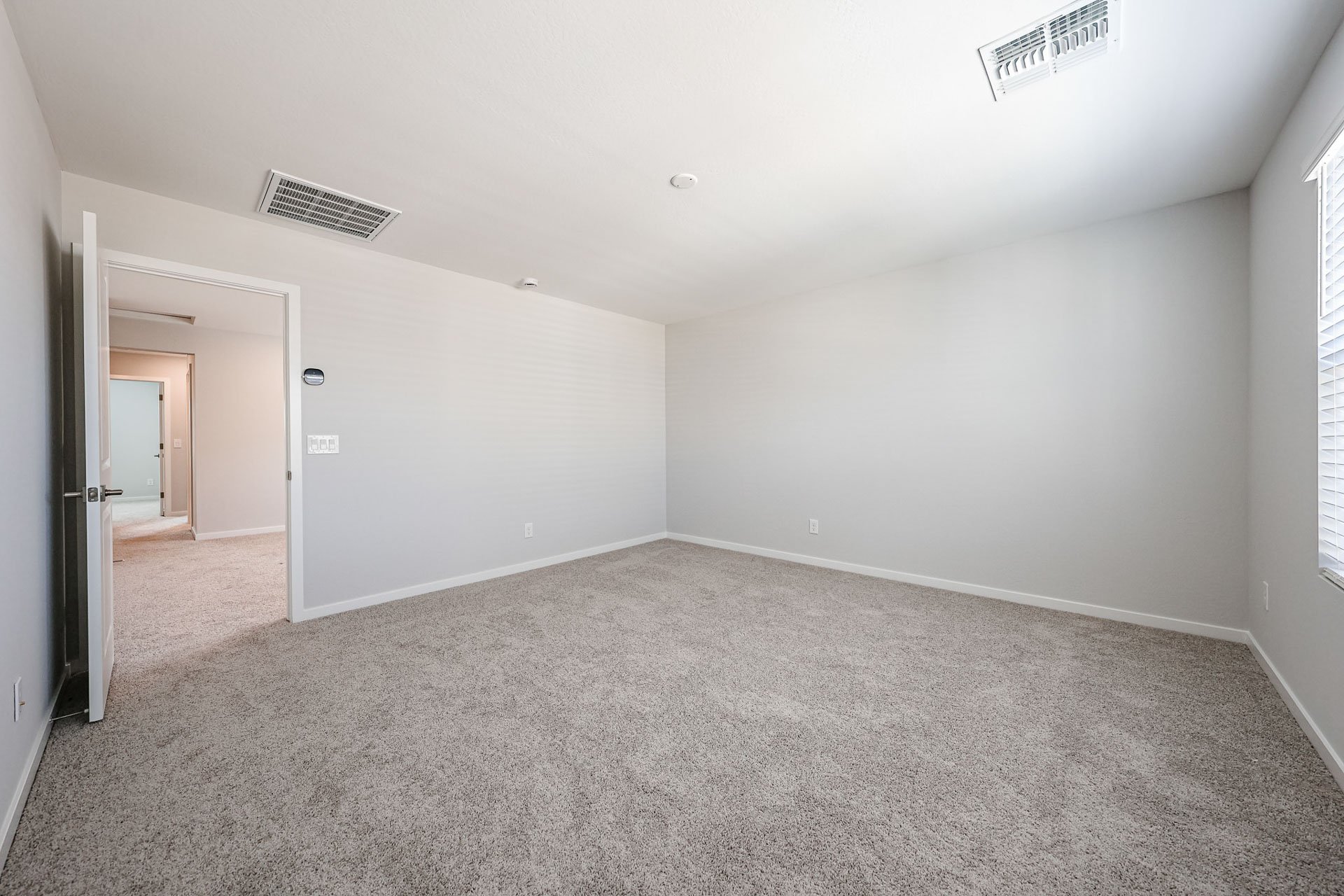 A room with a carpet and a vent.