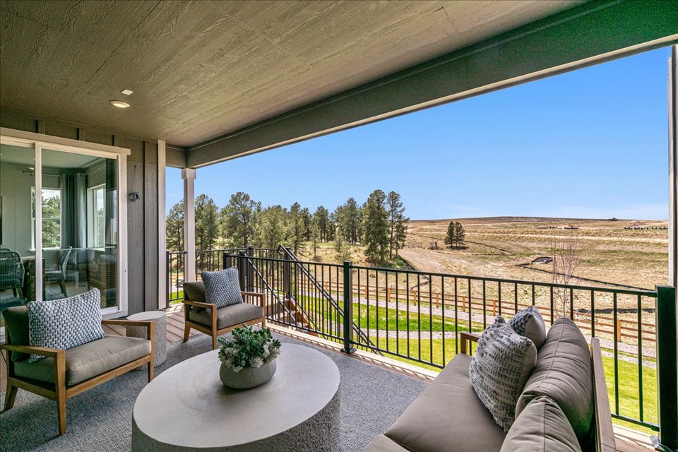 A deck with a view of a field and trees.