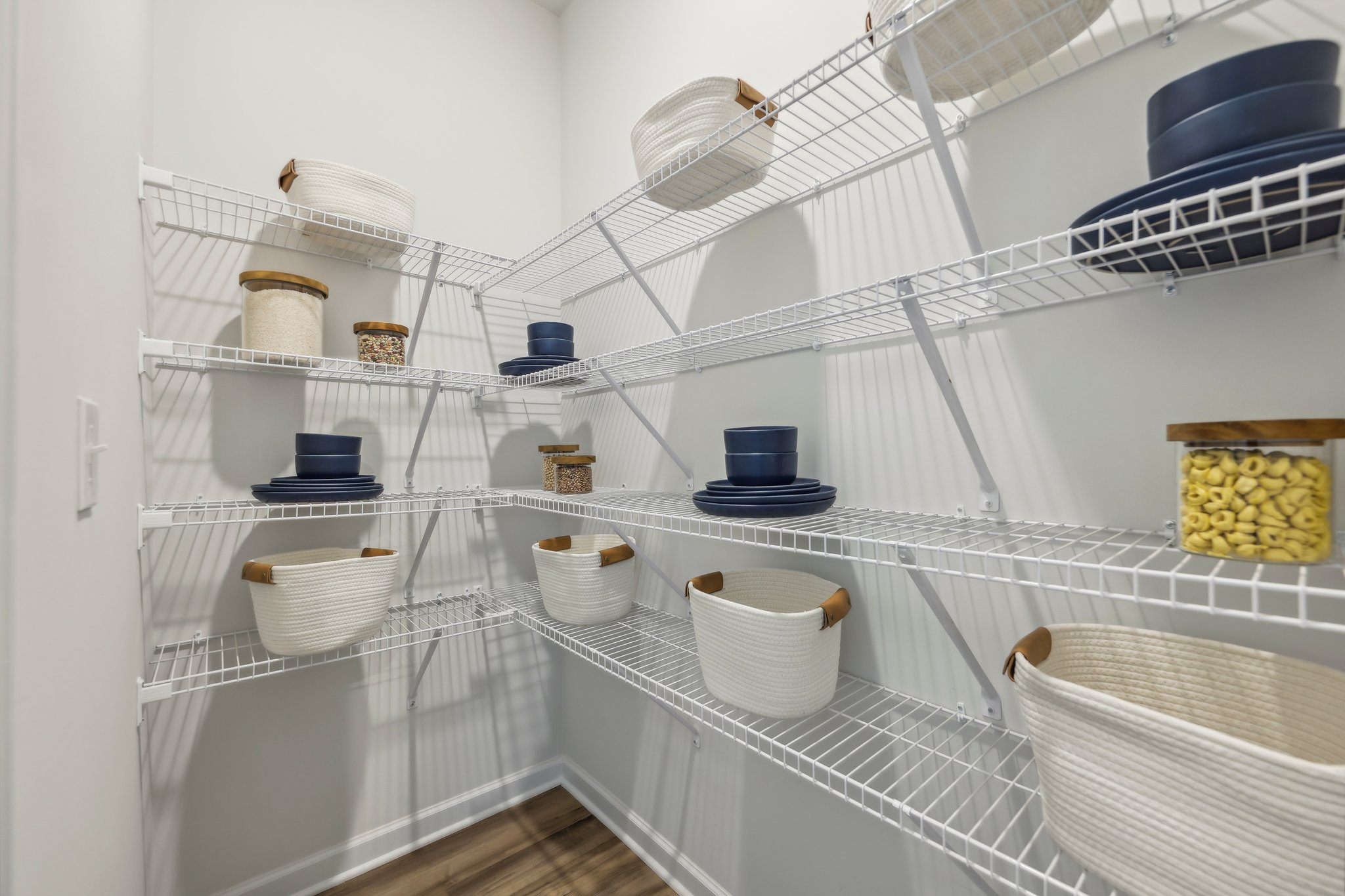 A white shelf with many white bowls and baskets on it.