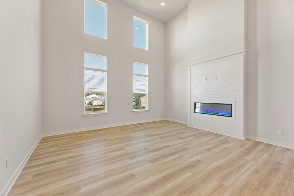 A room with a wood floor and a white wall with a television on it.