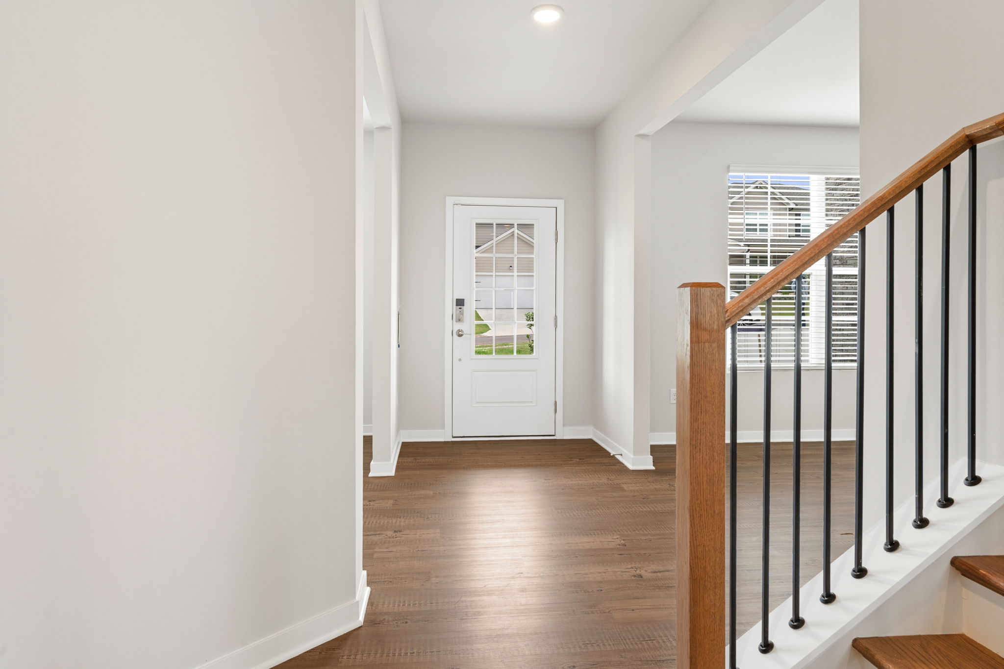 A white room with a wood floor and a black railing.