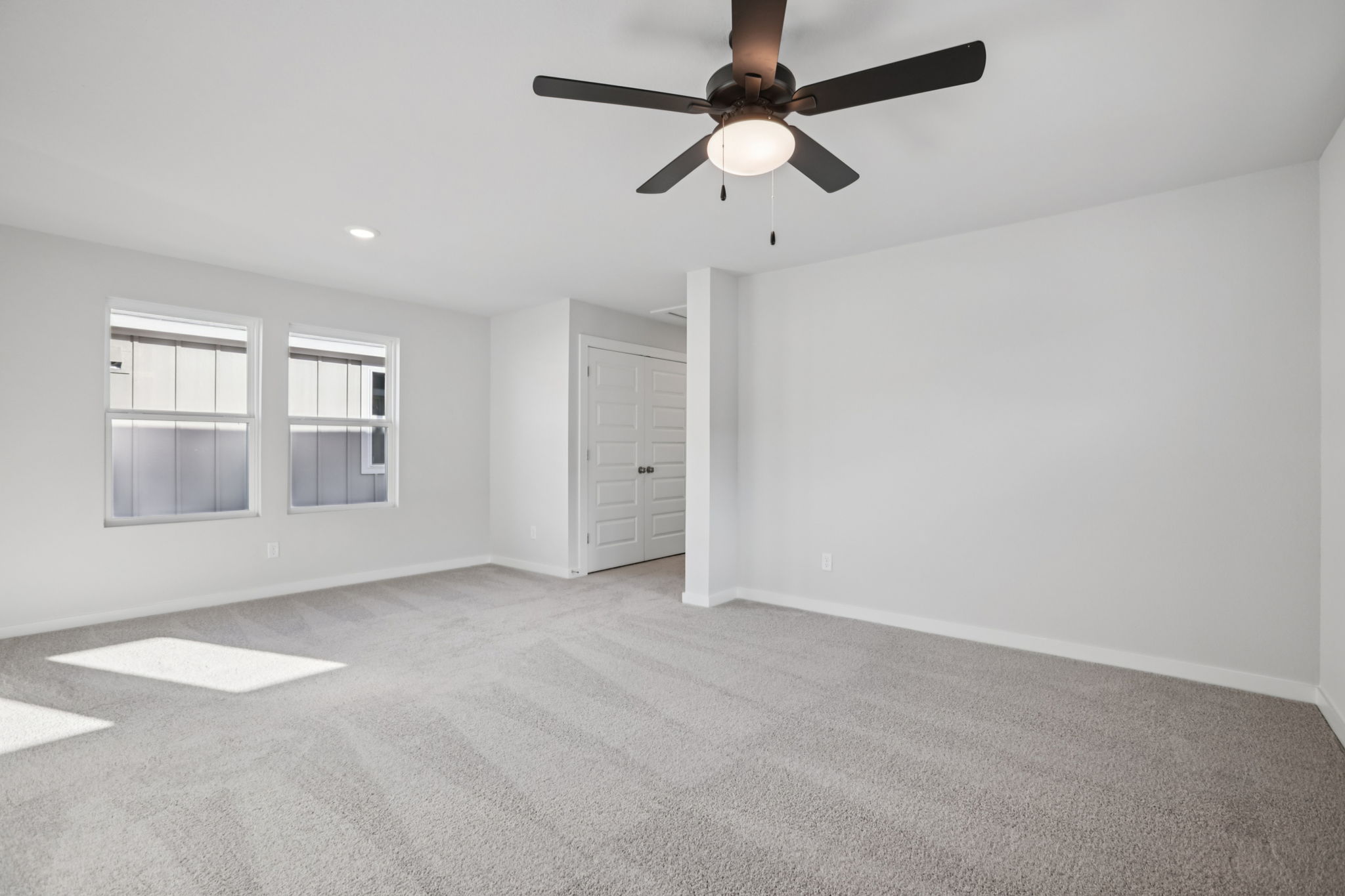 A room with a ceiling fan and a door.