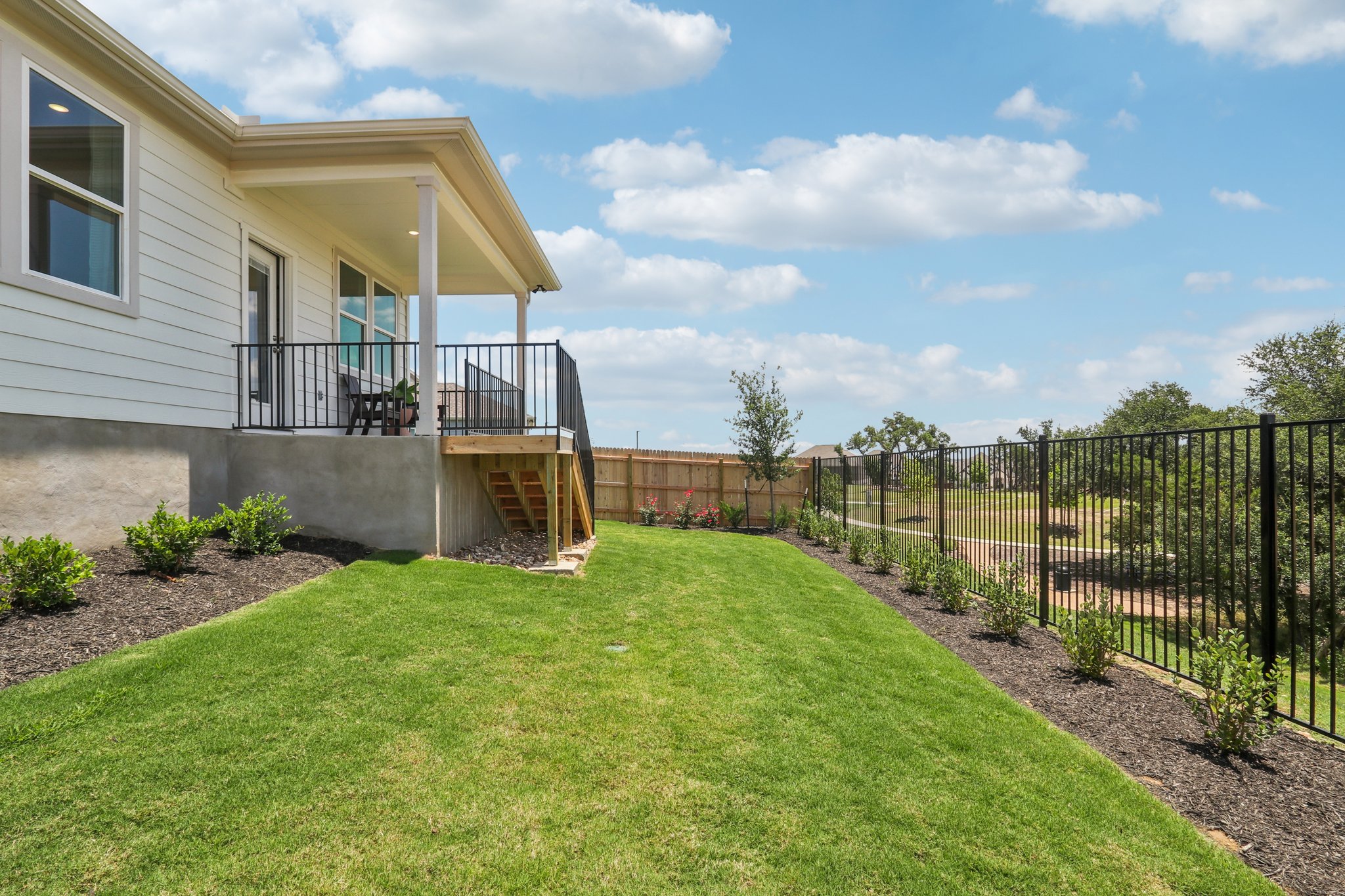 A house with a fence and a lawn in front of it.