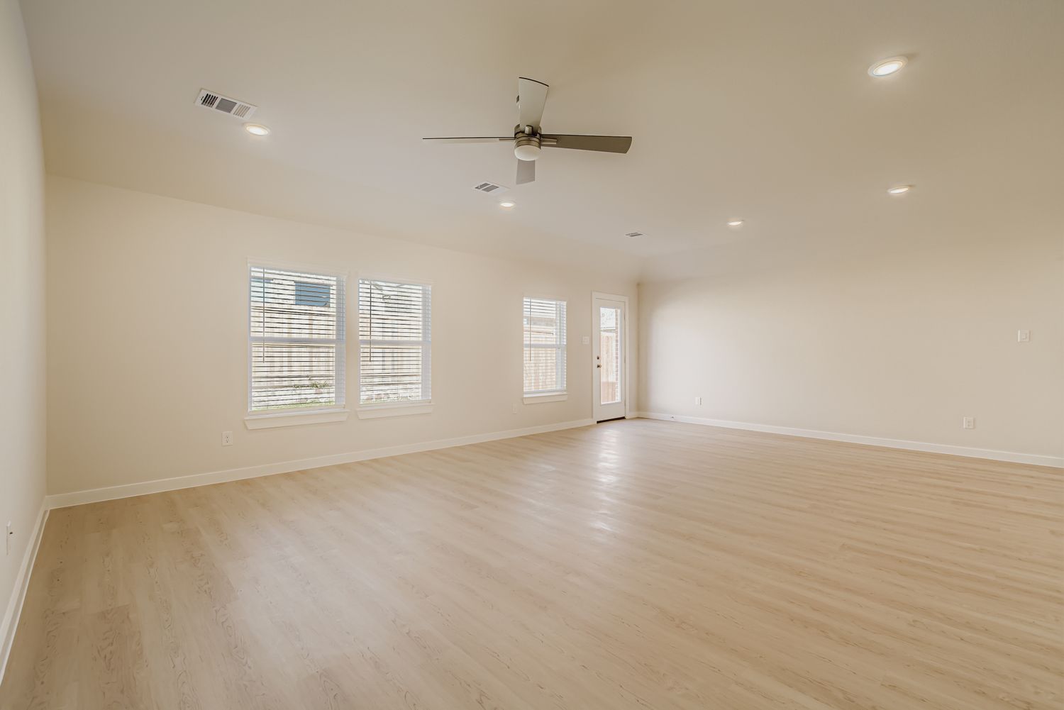 A room with a ceiling fan and a wood floor.