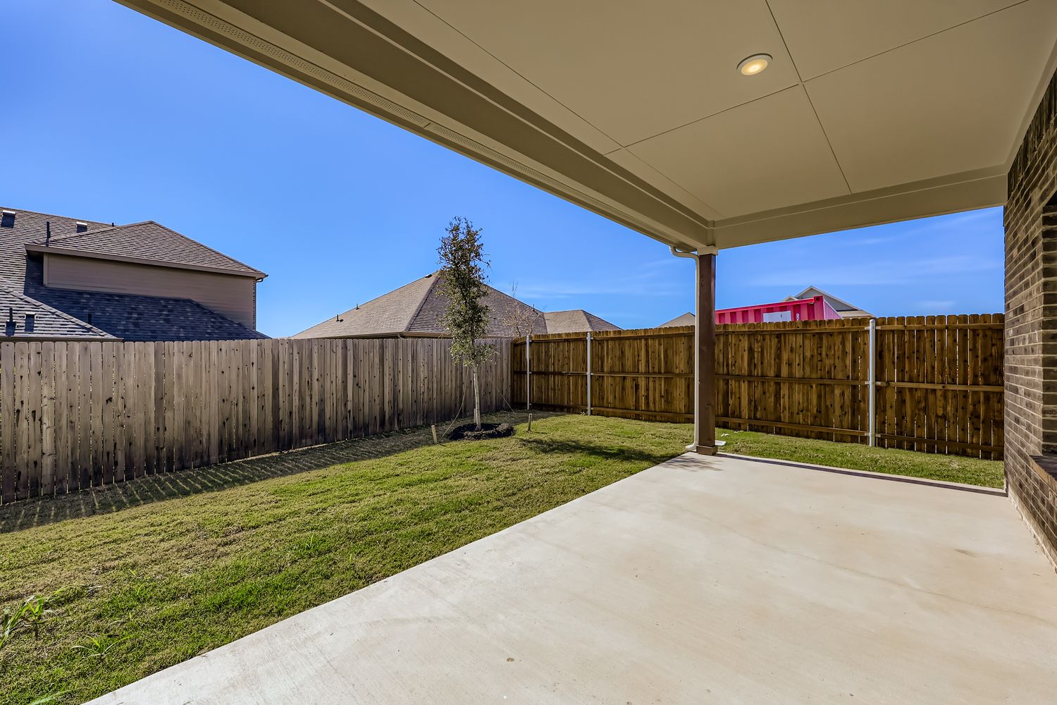 A fenced in yard with a wood fence and a tree.