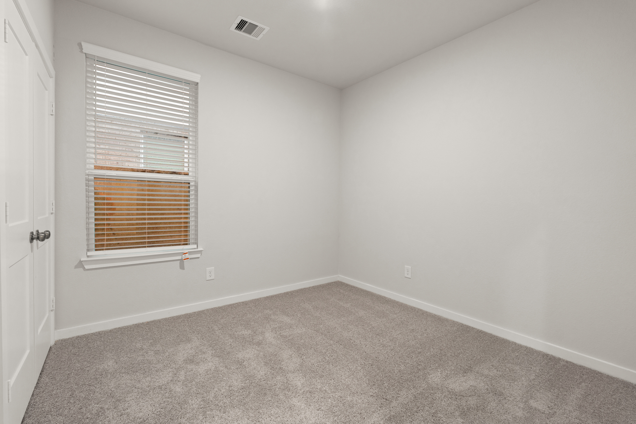 A room with a carpet and a window.