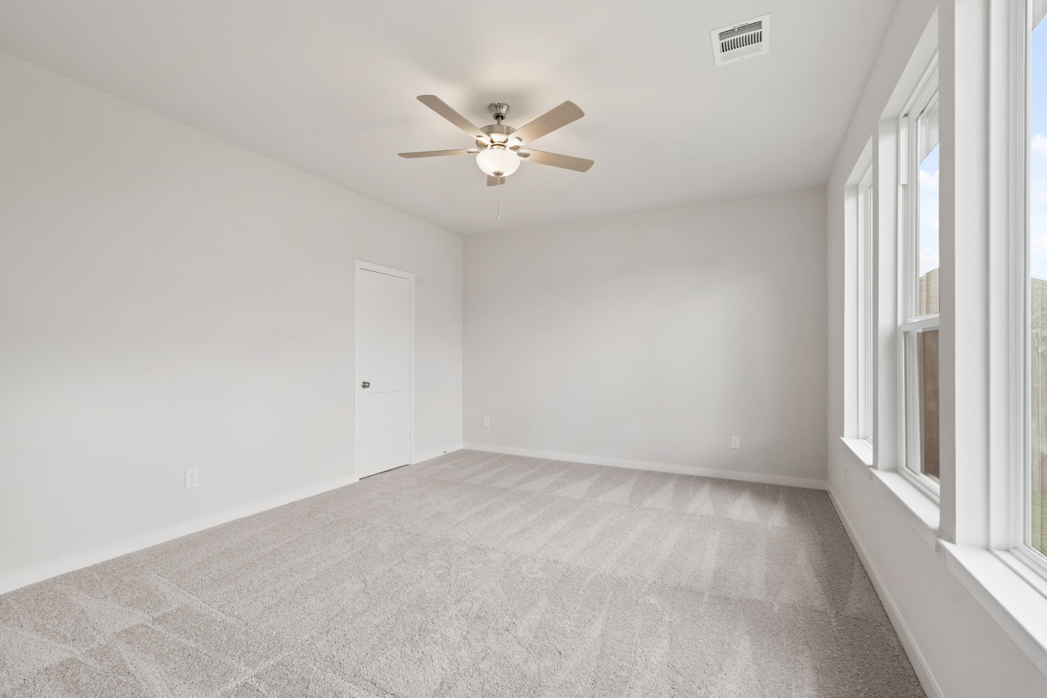 A room with a ceiling fan and a door.