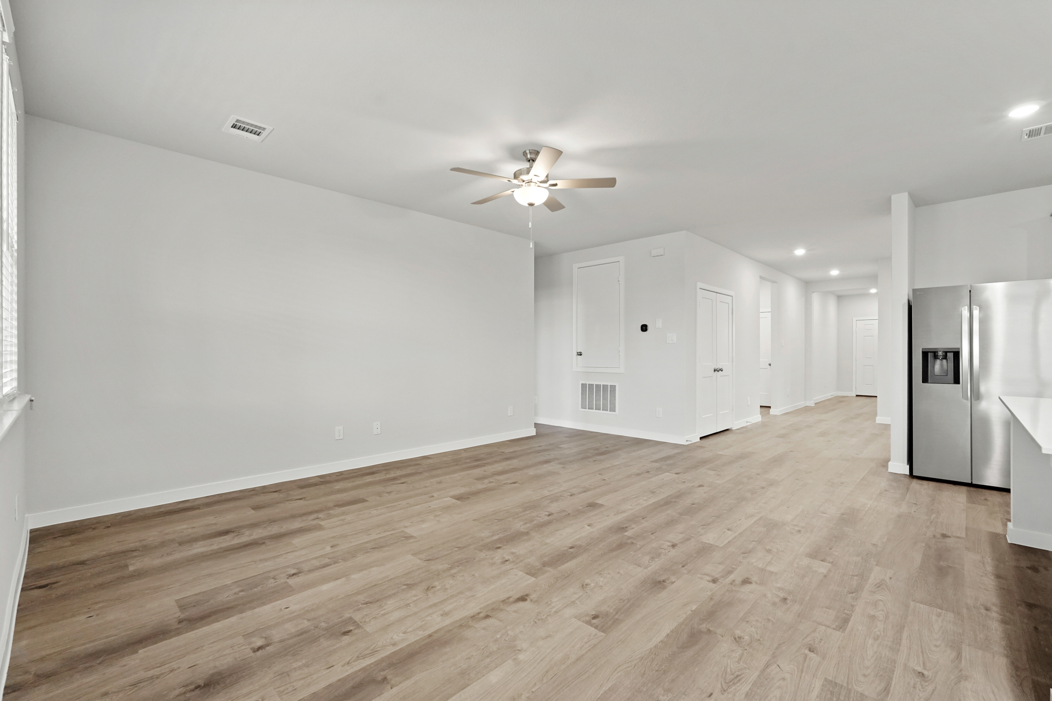 A large empty room with a wood floor and a ceiling fan.