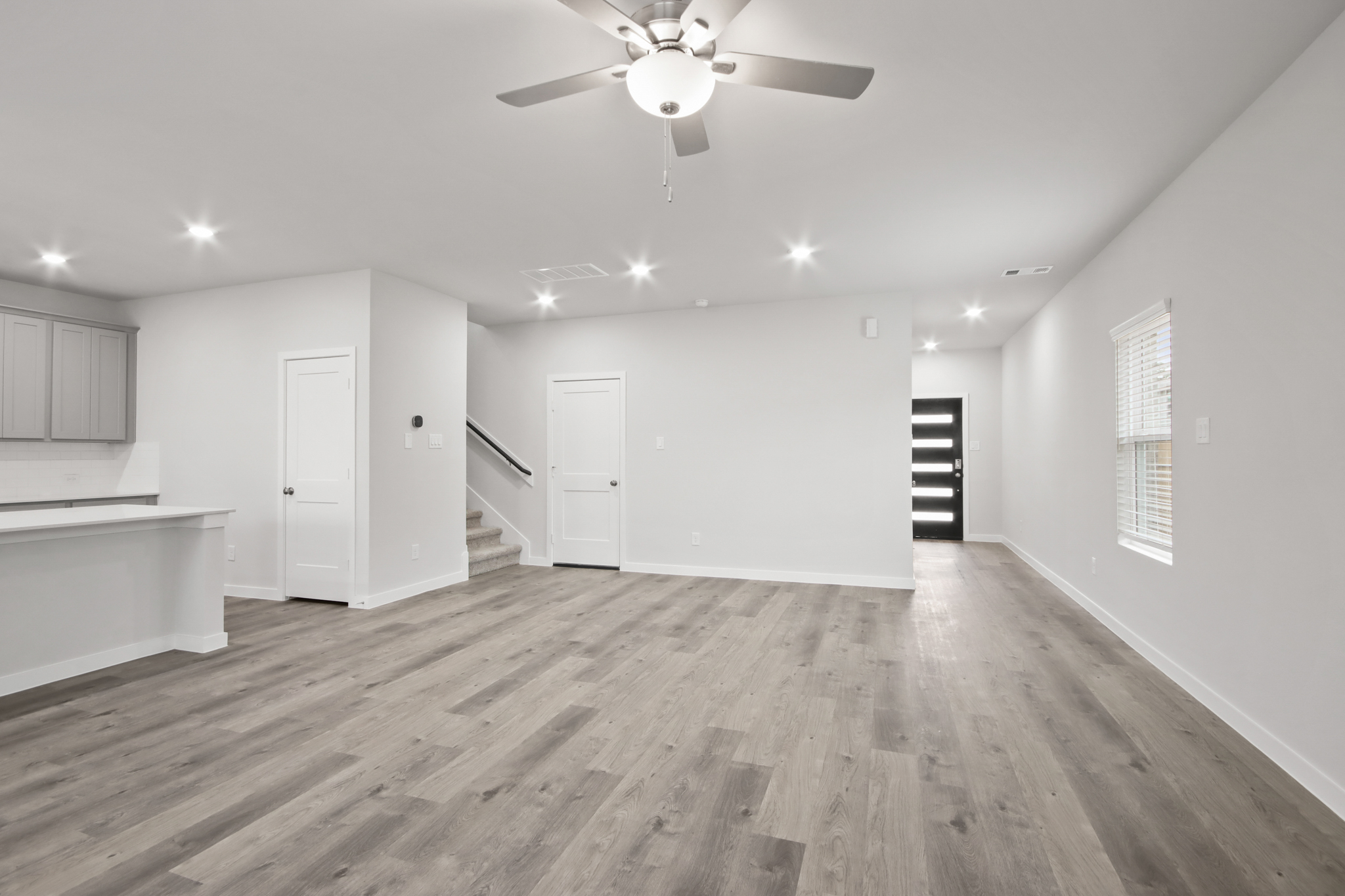 A large empty room with a ceiling fan and a wood floor.