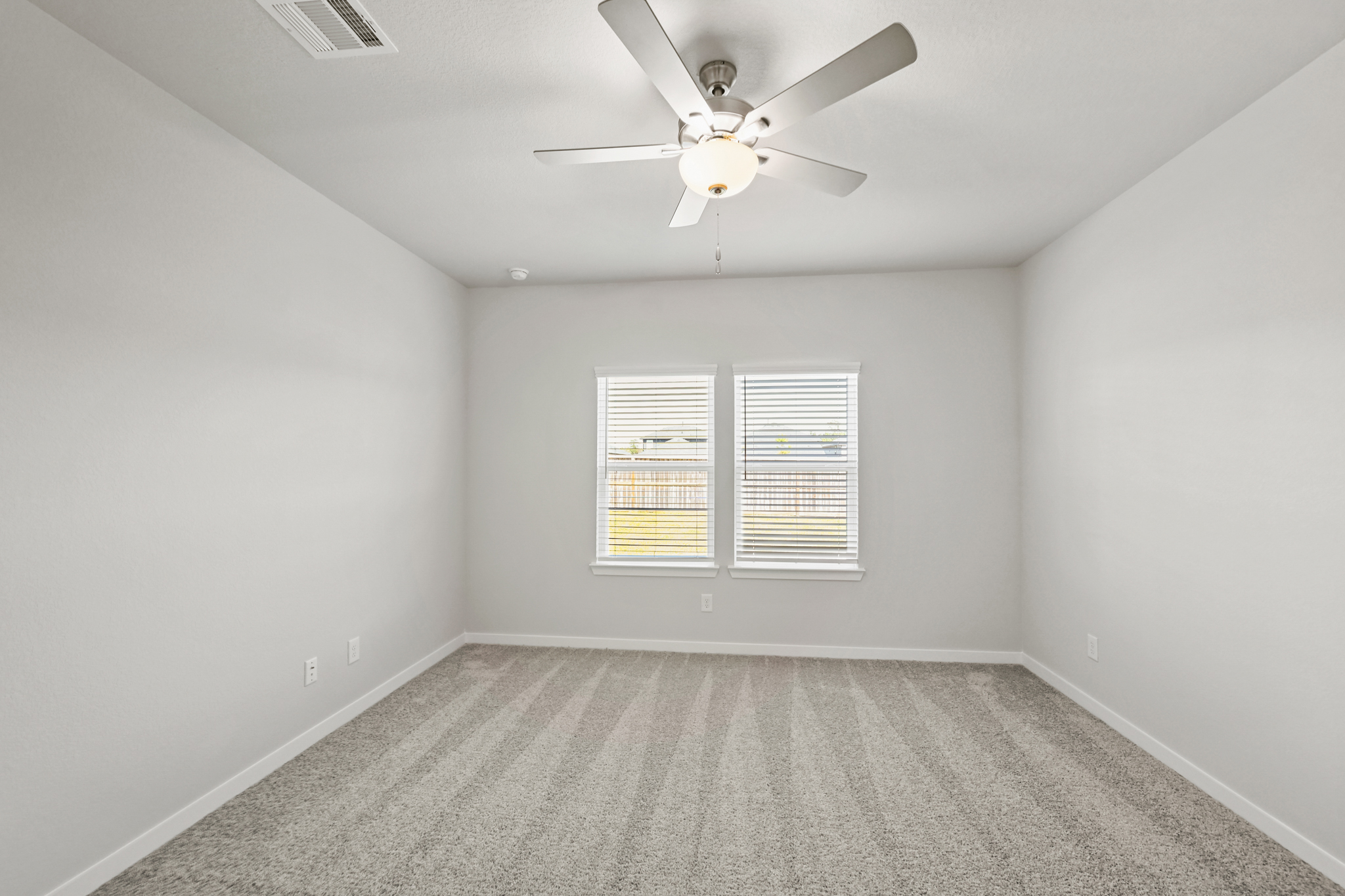 A room with a ceiling fan and a window.