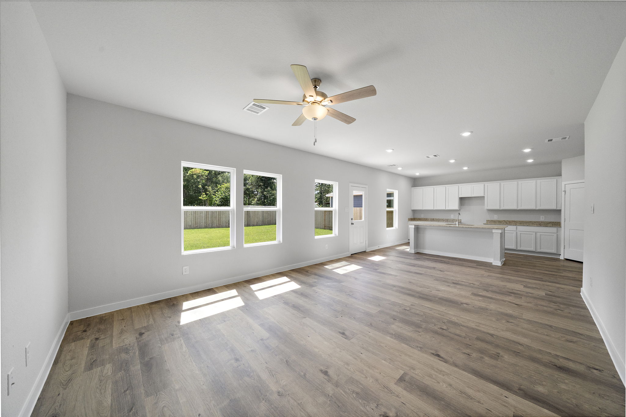 A large empty room with a ceiling fan and a wood floor.