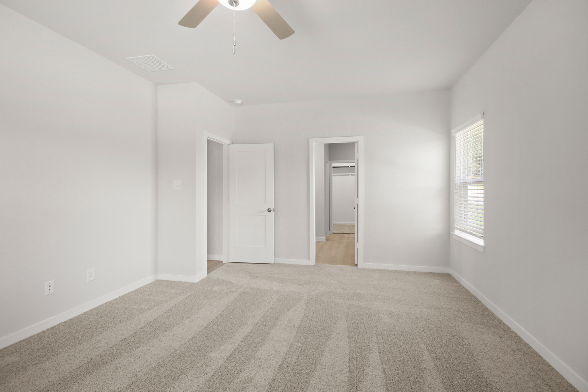 A room with a ceiling fan and a door.