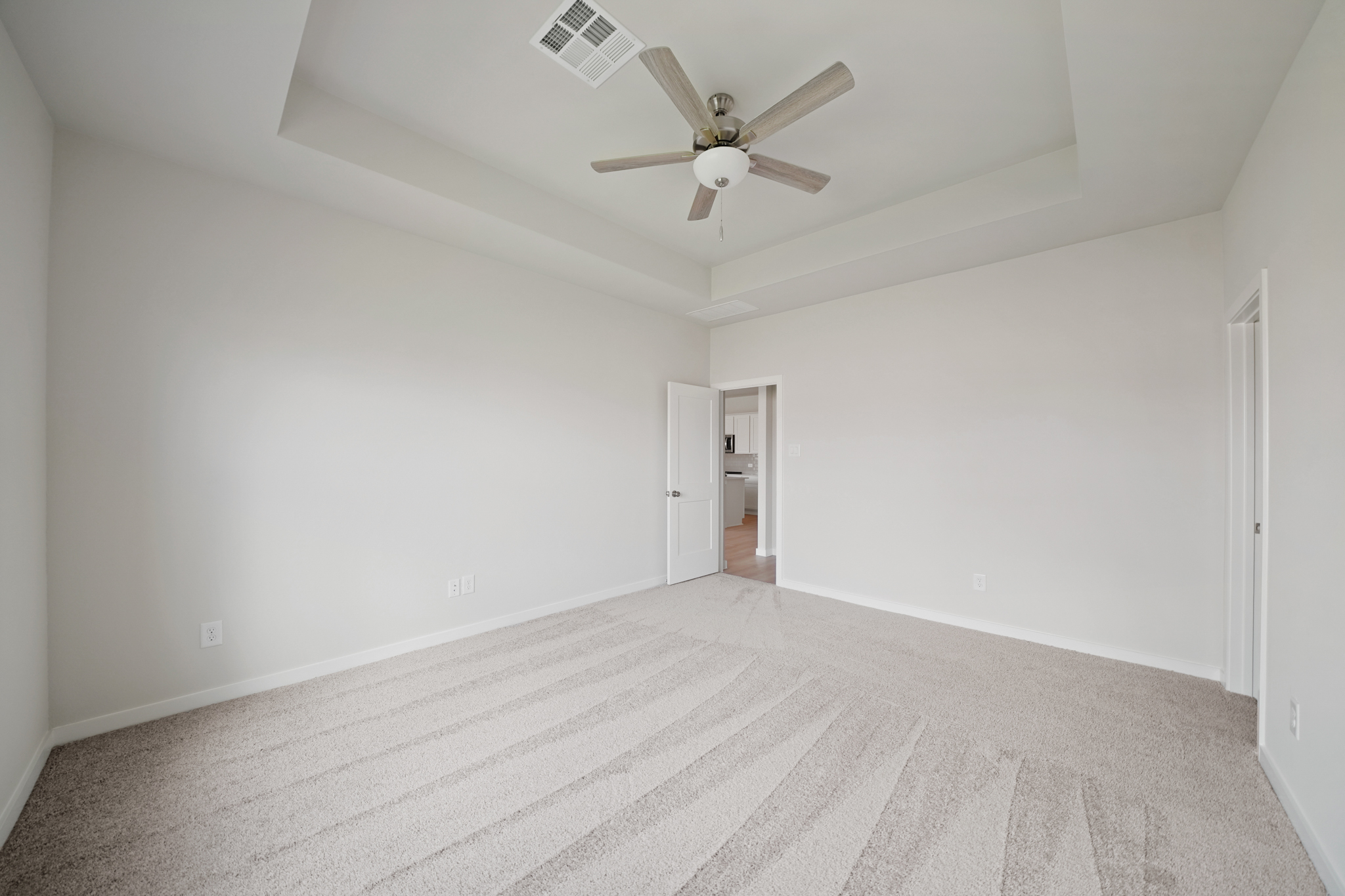 A room with a ceiling fan and a carpet.