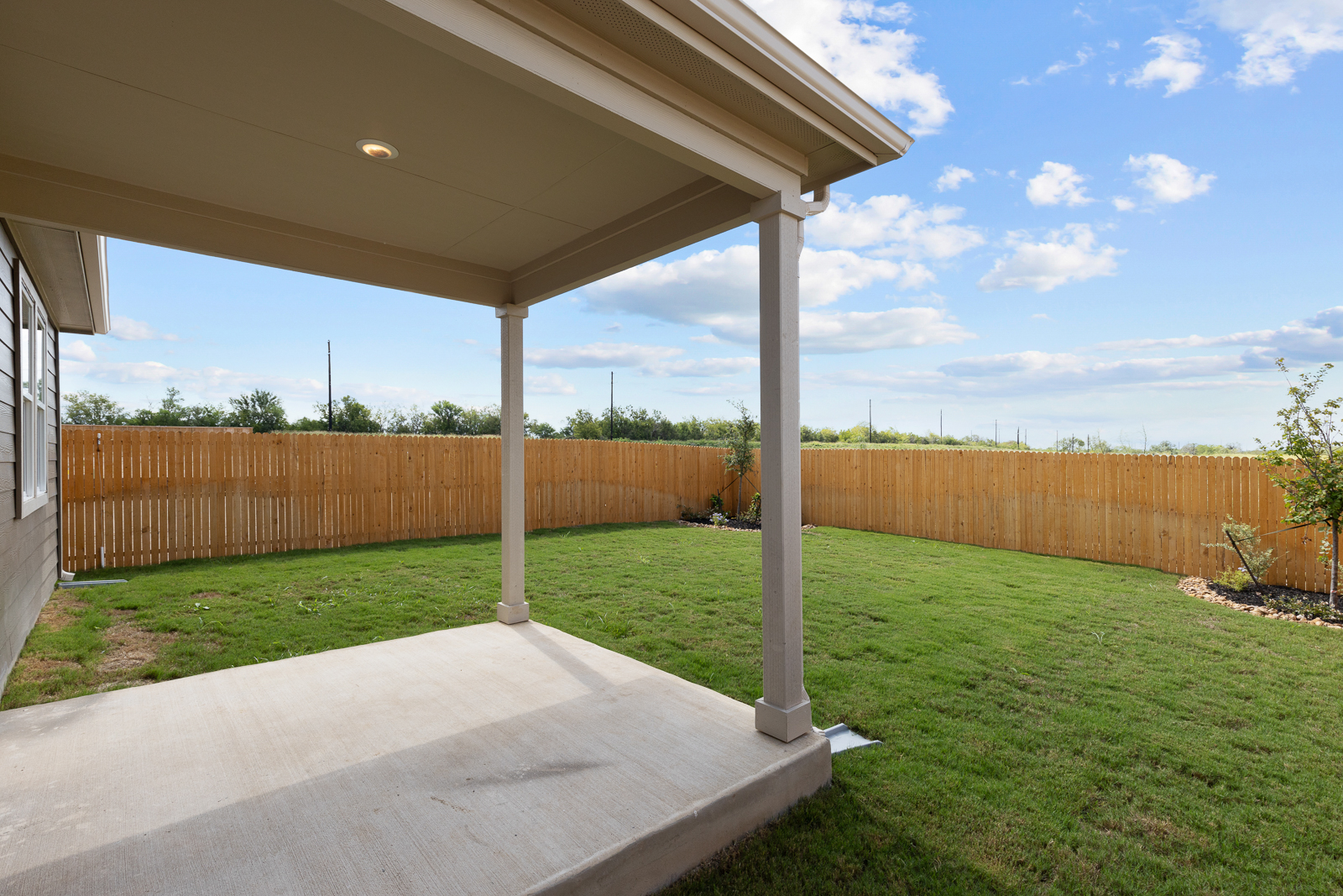 A covered patio with a fence and a wood fence.