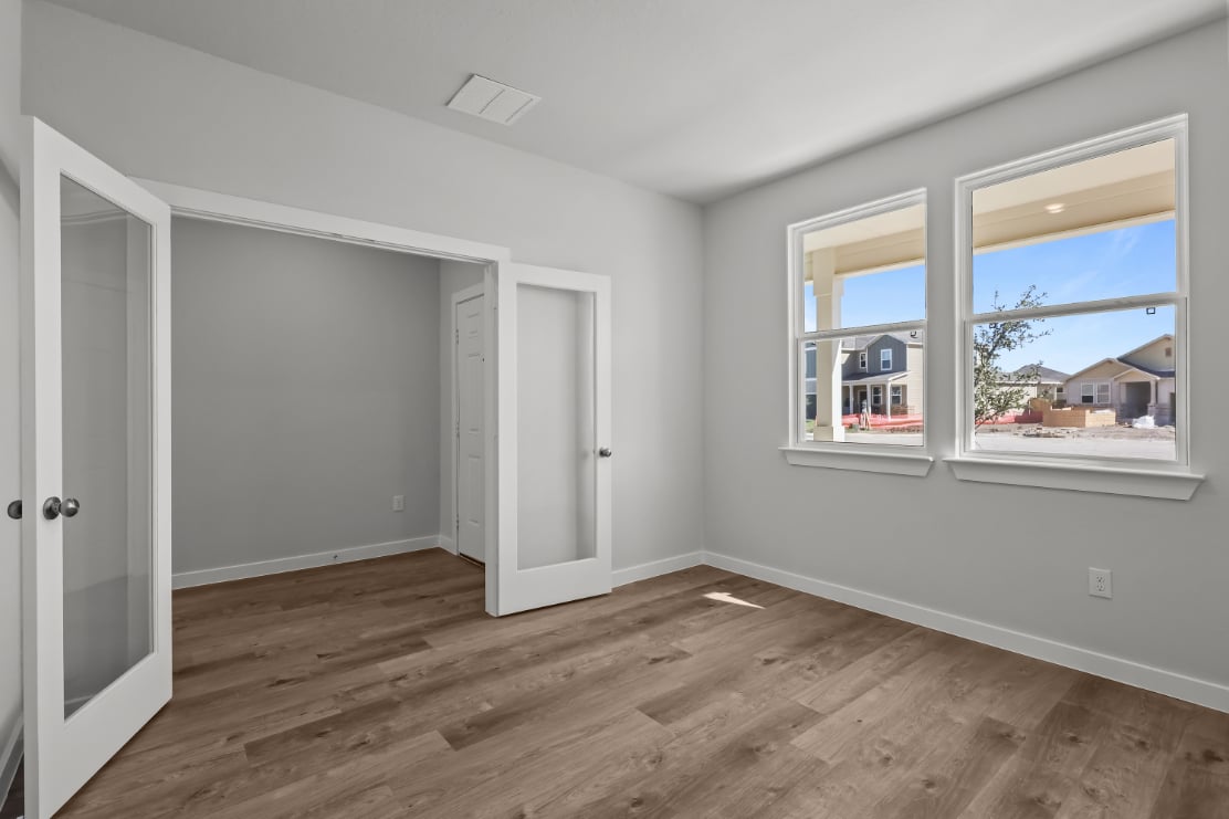 A room with a wood floor and a window with a view of the ocean.