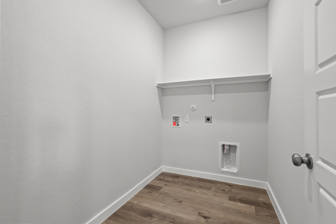 A white wall with a door and a wood floor.