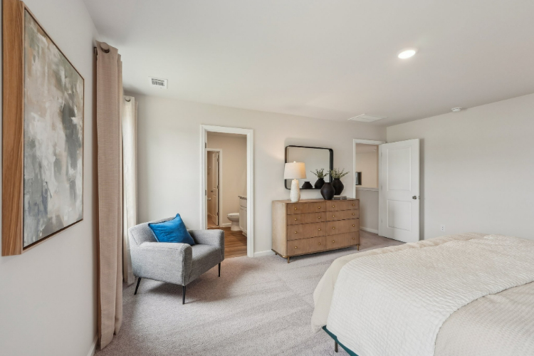 A bedroom with a bed and a chair.