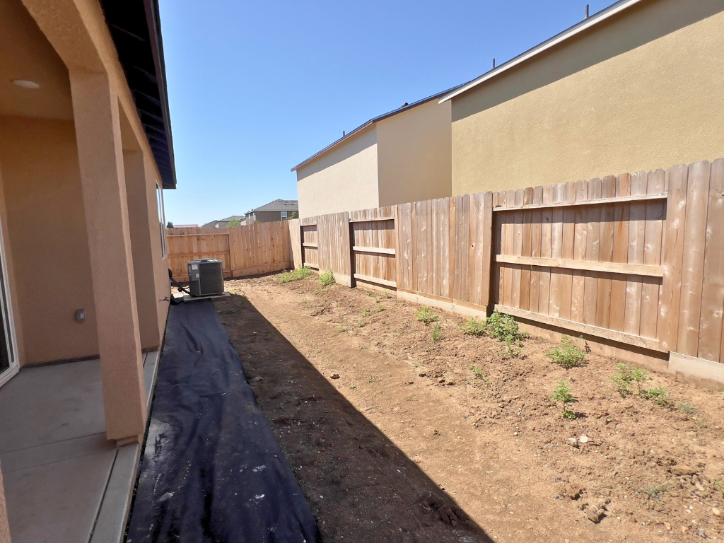 A fenced off area with a dirt path and a building.